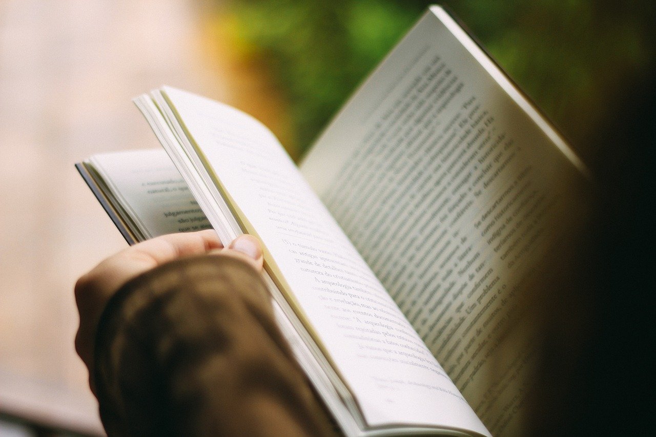 Unas manos sujetando un libro para leer a personas mayores
